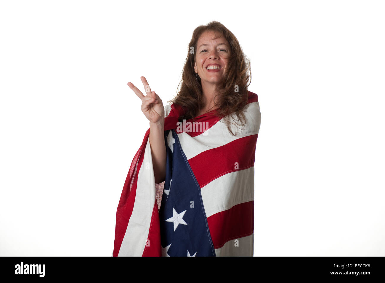 Frau eingewickelt in amerikanische Flagge Lächeln zeigt Victory-Zeichen mit den Fingern Stockfoto