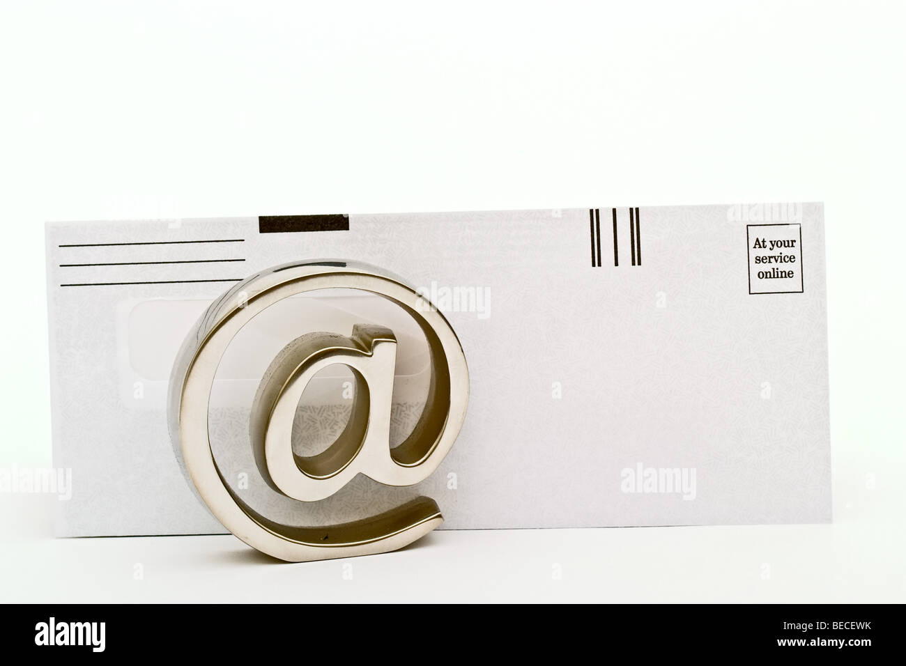 Metallische e-Mail-Symbol vor einem Papierumschlag Stockfoto