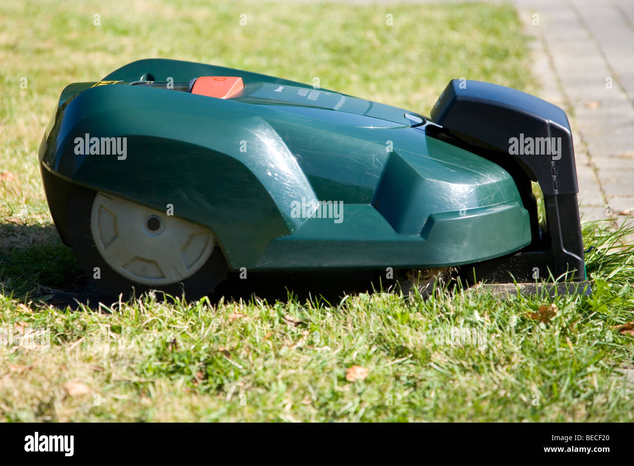 Grüne automatische Roboter Rasenmäher in der Ladestation in der Nähe einer  Terrasse angedockt, Seitenansicht Stockfotografie - Alamy