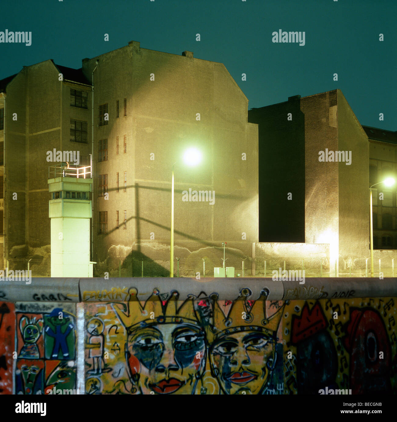Berliner Mauer mit Graffiti, Wachturm und beleuchtete Niemandsland in den Rücken, Berlin, Deutschland Stockfoto