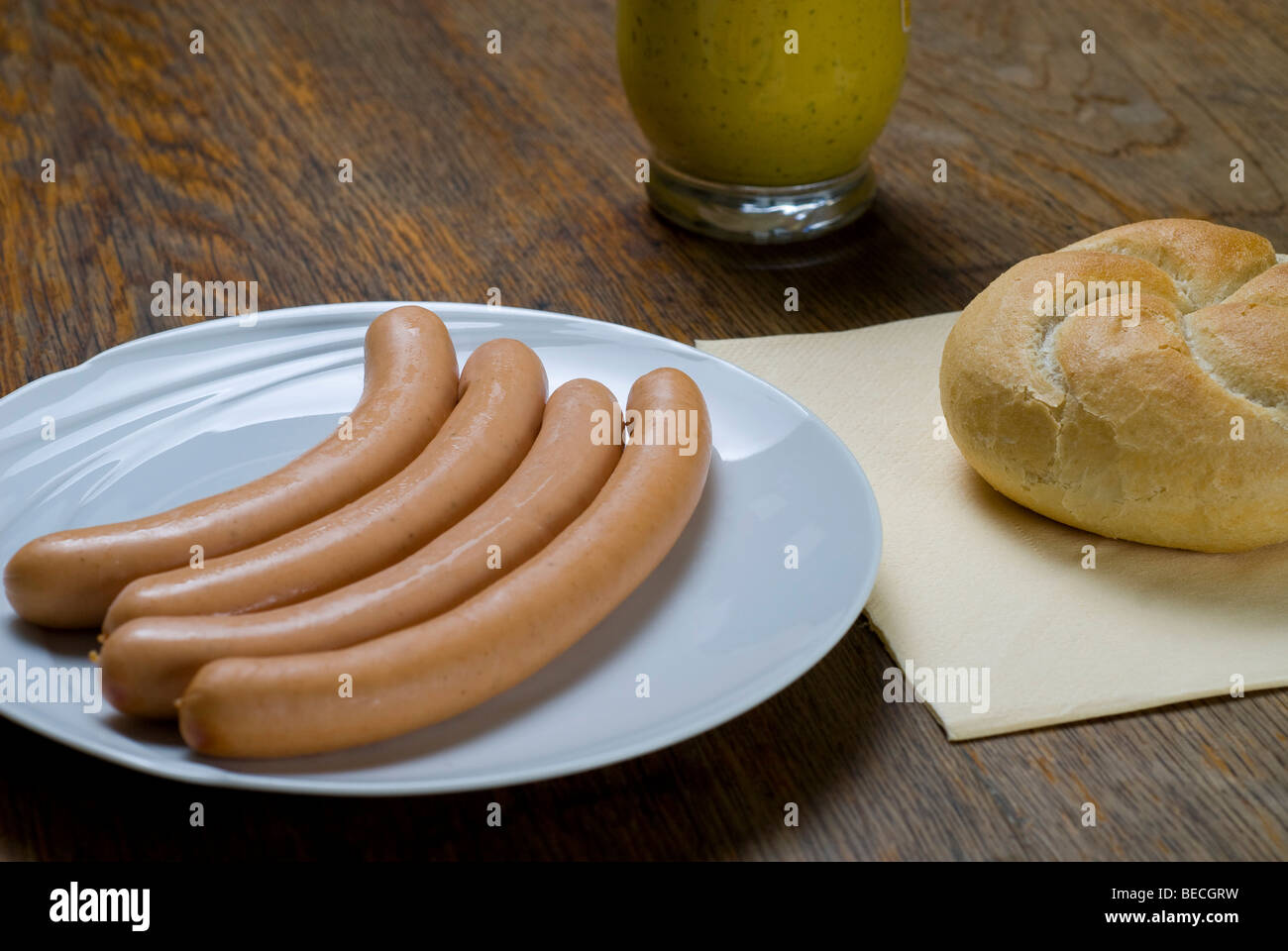 Wiener Würstchen mit Semmel Roll und ein Glas Senf Würze Stockfoto