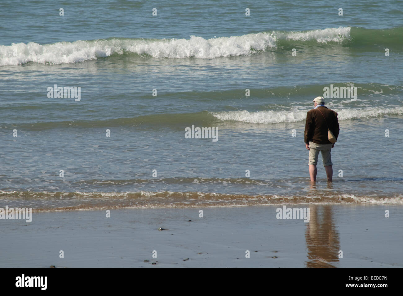 September nachmittags - Indian Summer - ein applying Mann paddeln in den Wellen des Meeres in Tywyn Gwynedd Nord wales UK Stockfoto