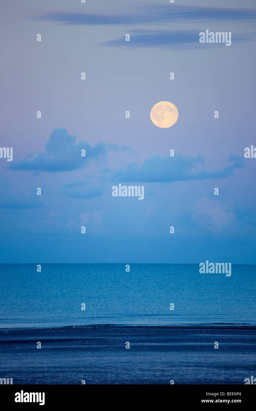 Großbritannien UK. Oktober voll Mond steigt in den Himmel über dem Meer in der Abenddämmerung. Stockfoto