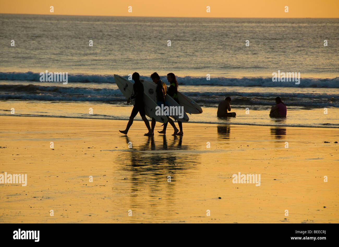 Surfer bei Sonnenuntergang am Strand von Kuta auf Bali Indonesien Stockfoto