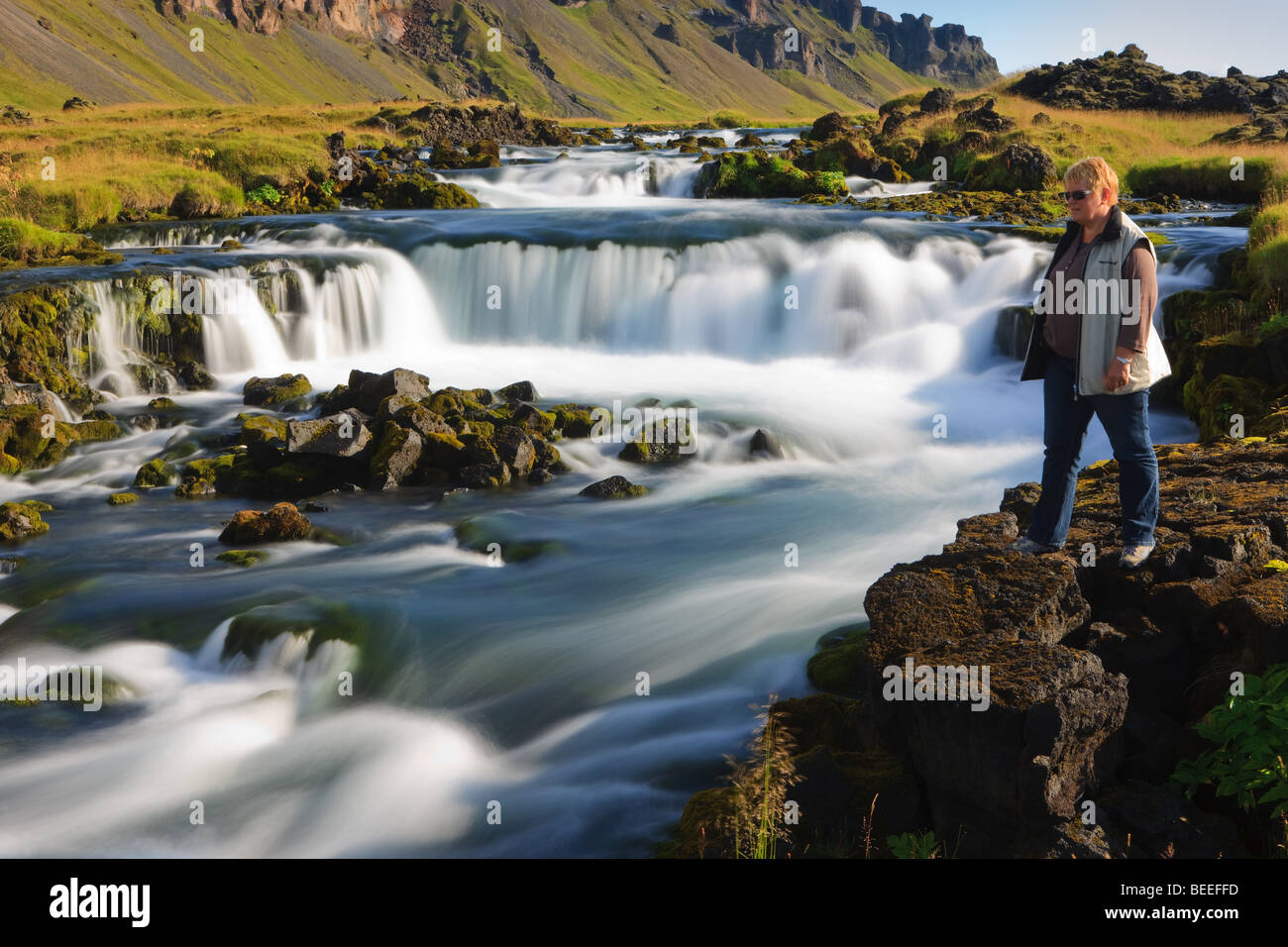 Frau am Wasserfall in der Nähe von Kirkjubaejarklaustur Stockfoto