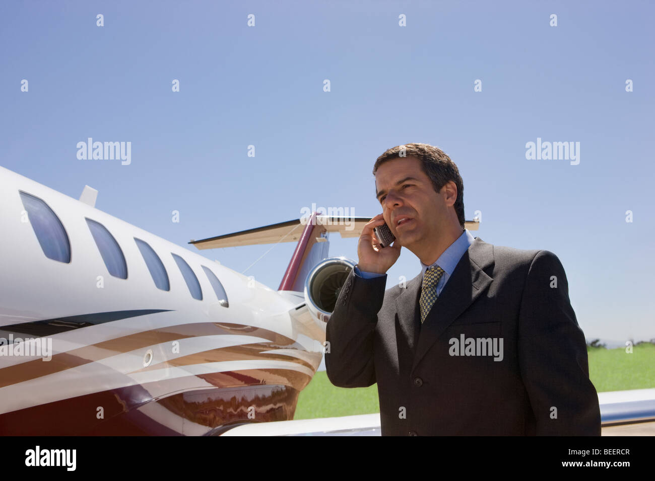 Hispano-Amerikaner Geschäftsmann mit Handy neben Privat-jet Stockfoto