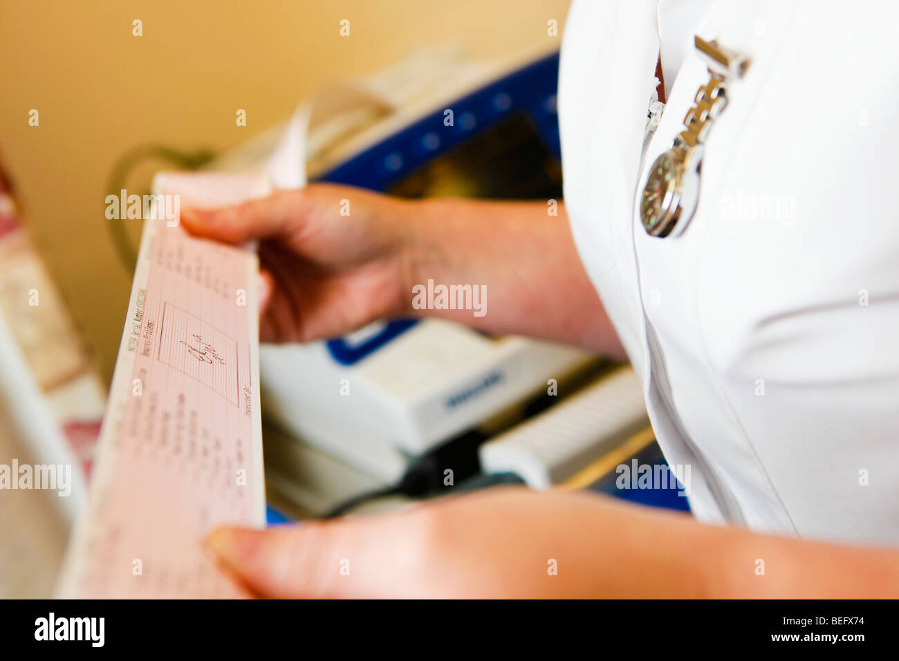 Krankenschwester, die einen Ausdruck von einem medizinischen Monitor lesen Stockfoto