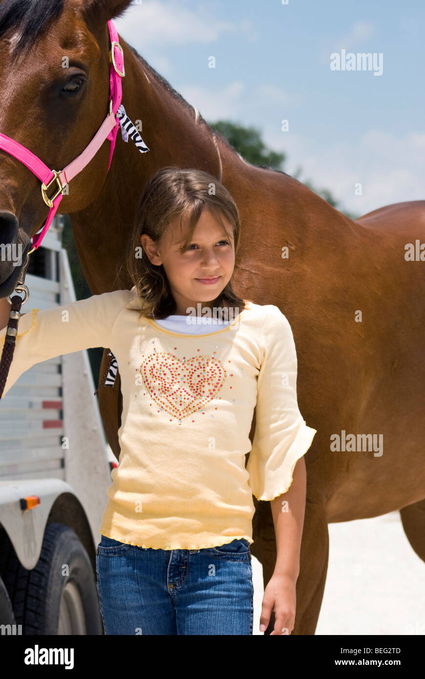Ein Pferd ohne Sattel und ein junges Mädchen stand vor ihm hält seine bunten Zaumzeug. Stockfoto
