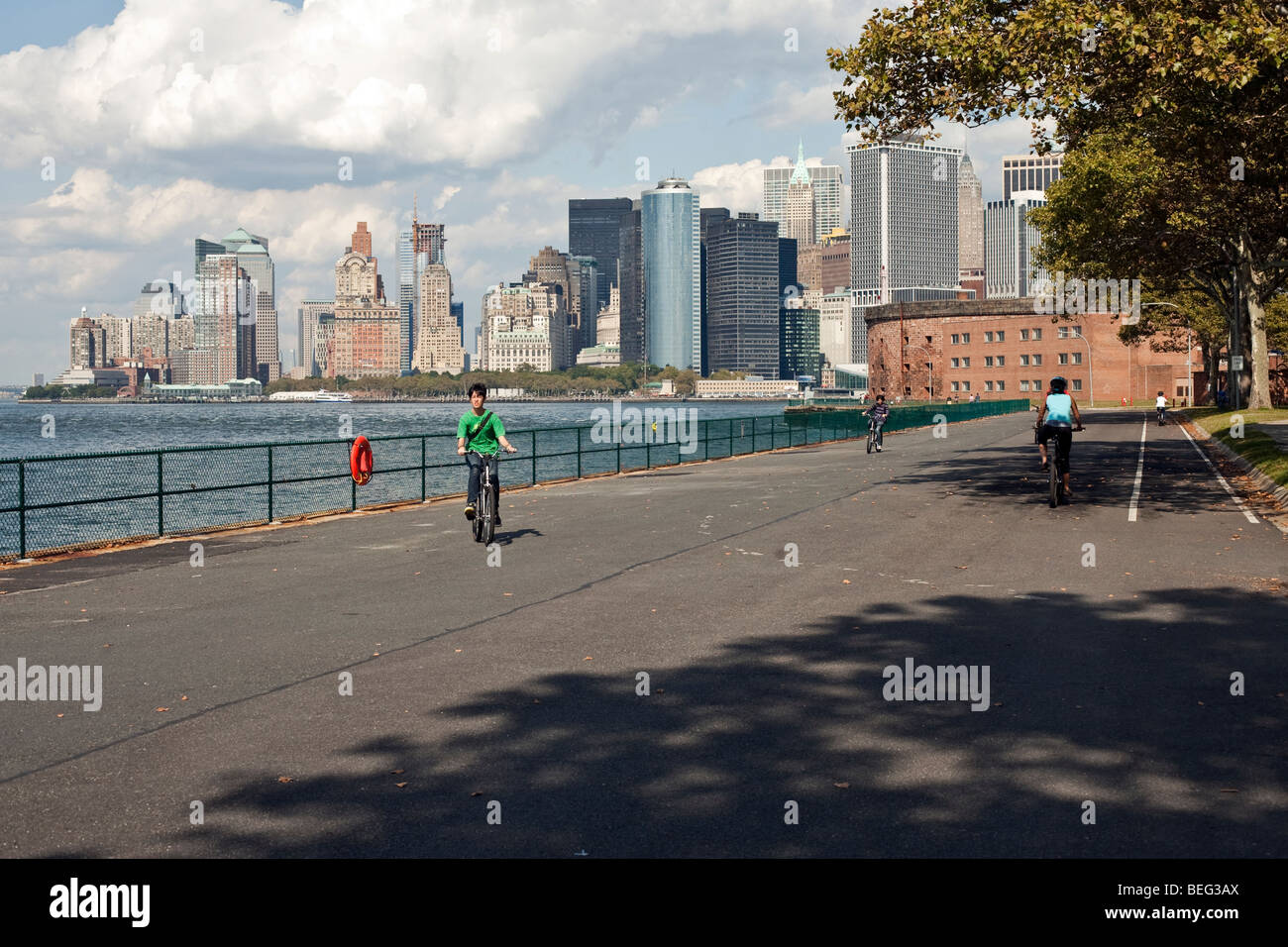 Radfahrer genießen die Promenade von Governors Island mit einen schönen Blick auf Schloss Williams & die Skyline von Lower Manhattan & waterfront Stockfoto