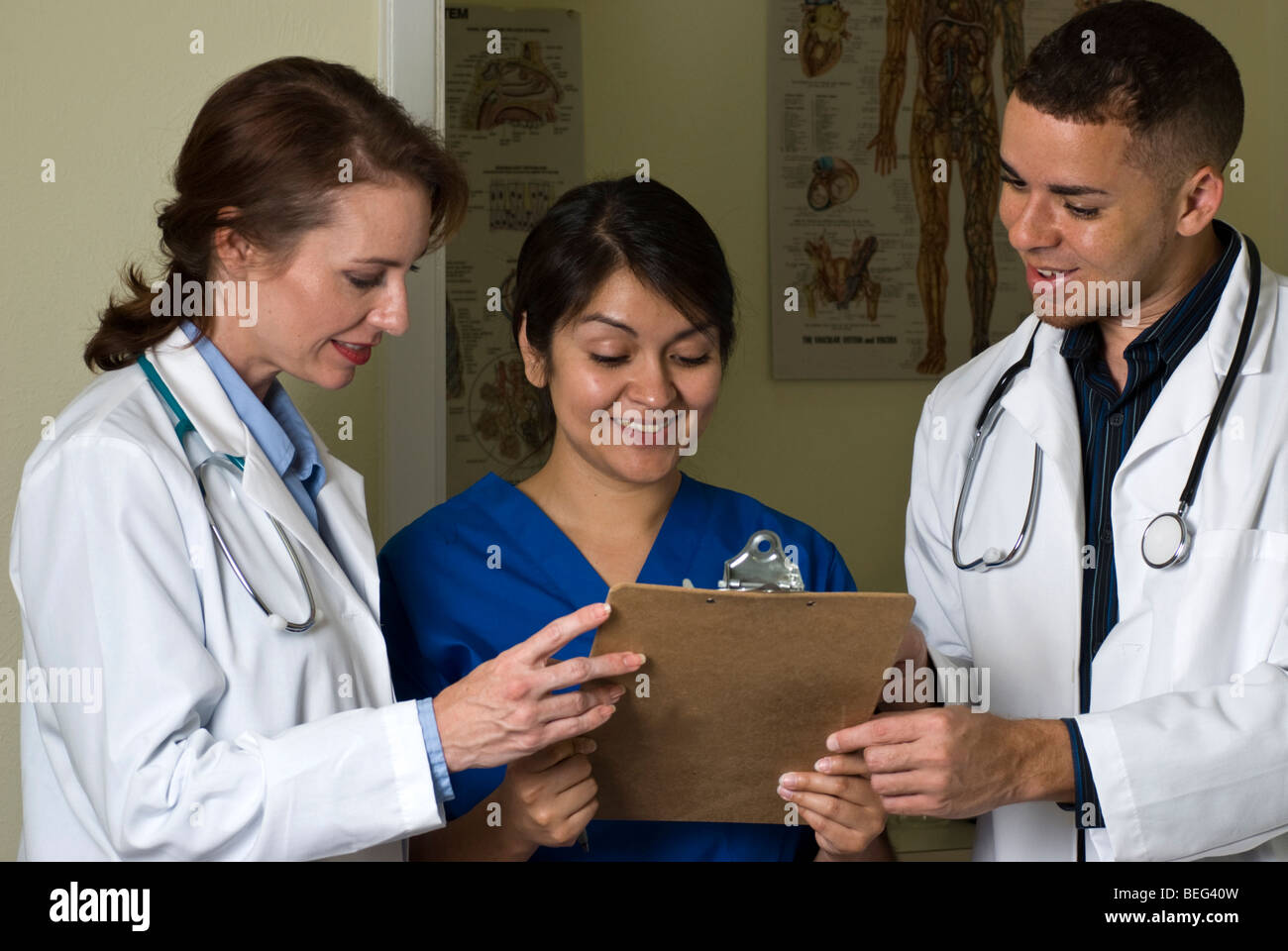 Zwei Ärzte und eine Krankenschwester, die lächelnd auf die Informationen, die sie überprüfen auf einem Klemmbrett. Stockfoto
