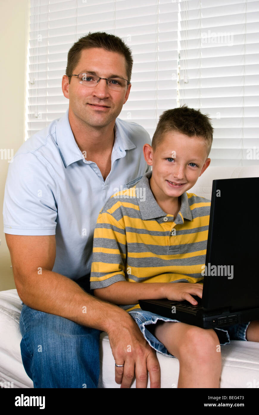 Ein junger Vater und sein Sohn verwende einen Laptop etwas im Internet nachschlagen. Stockfoto