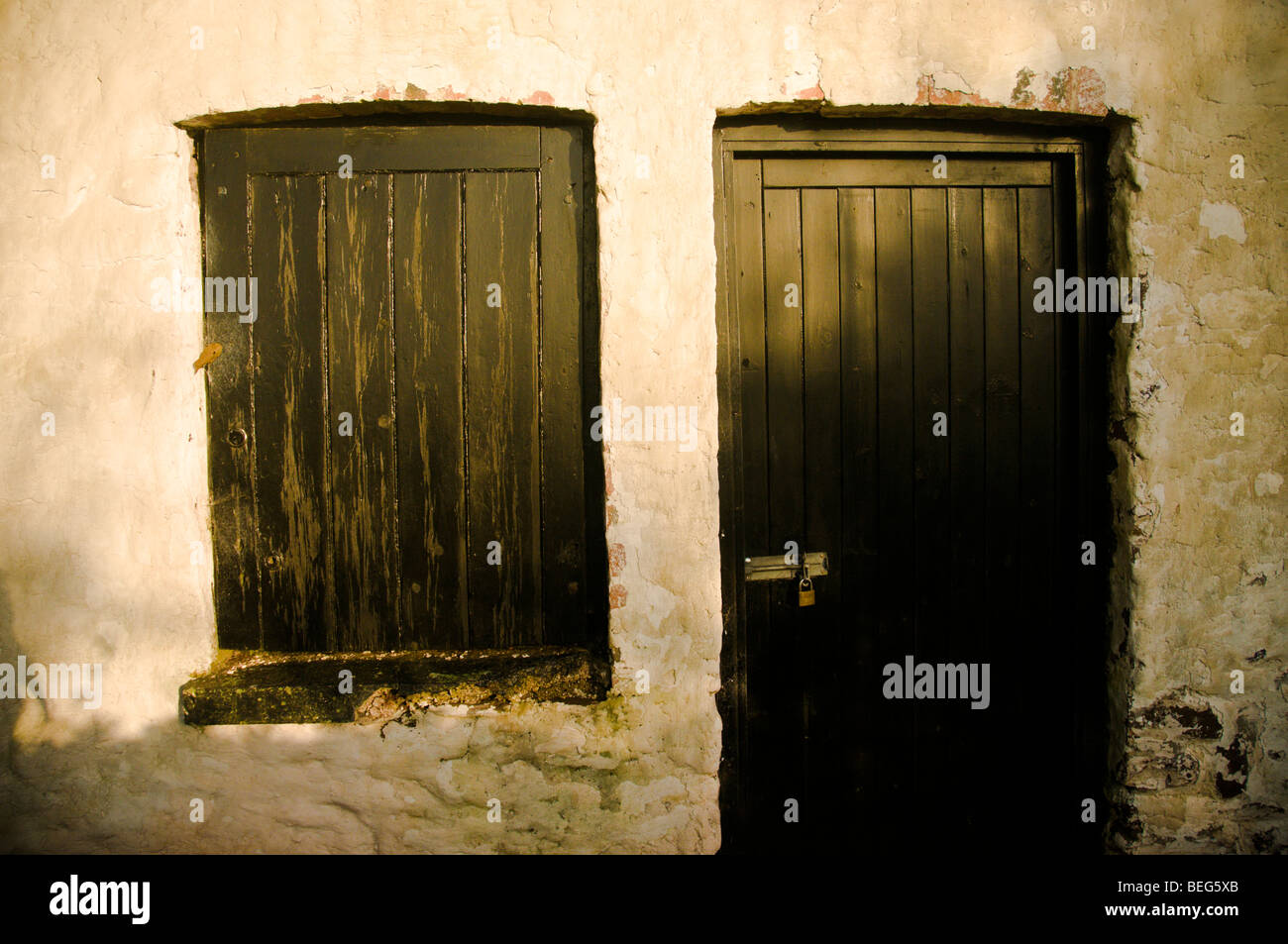 Tür und Fenster einer alten Scheune mit weiß getünchten Wänden Stockfoto