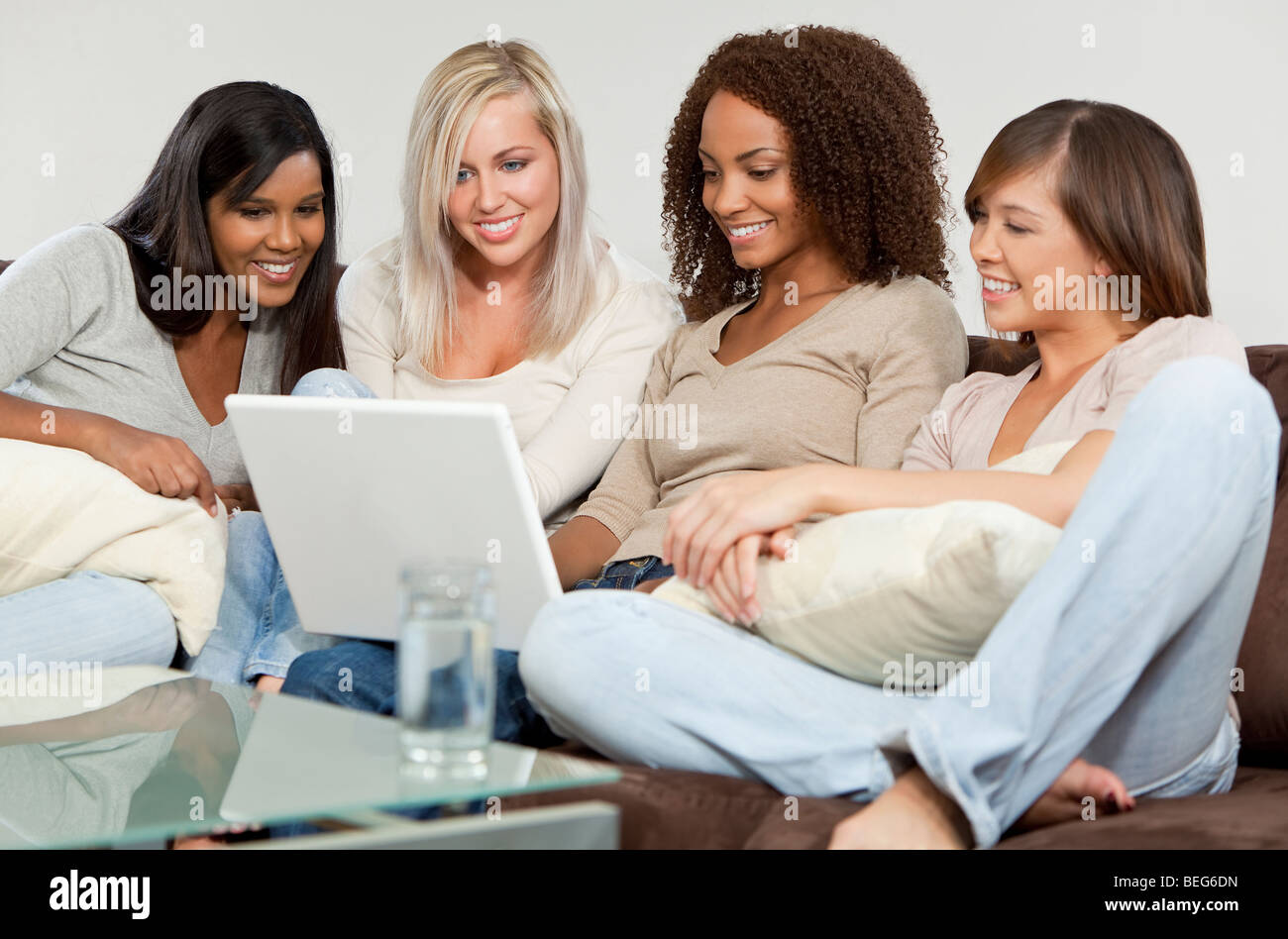 Vier gemischte Rennen Mädchen, ein Afroamerikaner, ein indischer, einem asiatischen und einem kaukasischen alle haben Spaß mit einem Laptopcomputer Stockfoto