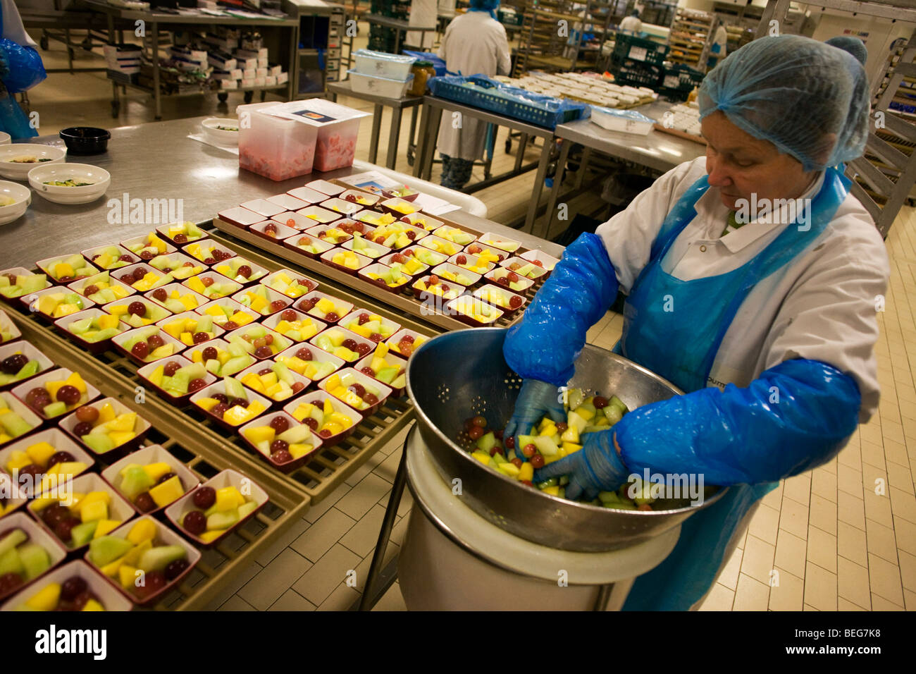 Eine Arbeitnehmerin bereitet Obstsalate bestimmt für Airline Mahlzeiten von Gate Gourmet am Flughafen Heathrow. Stockfoto