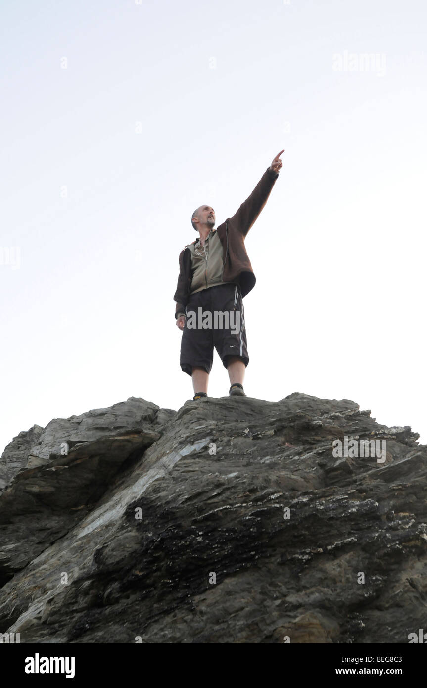 Ein Mann auf einem Felsen zeigt auf etwas Stockfoto