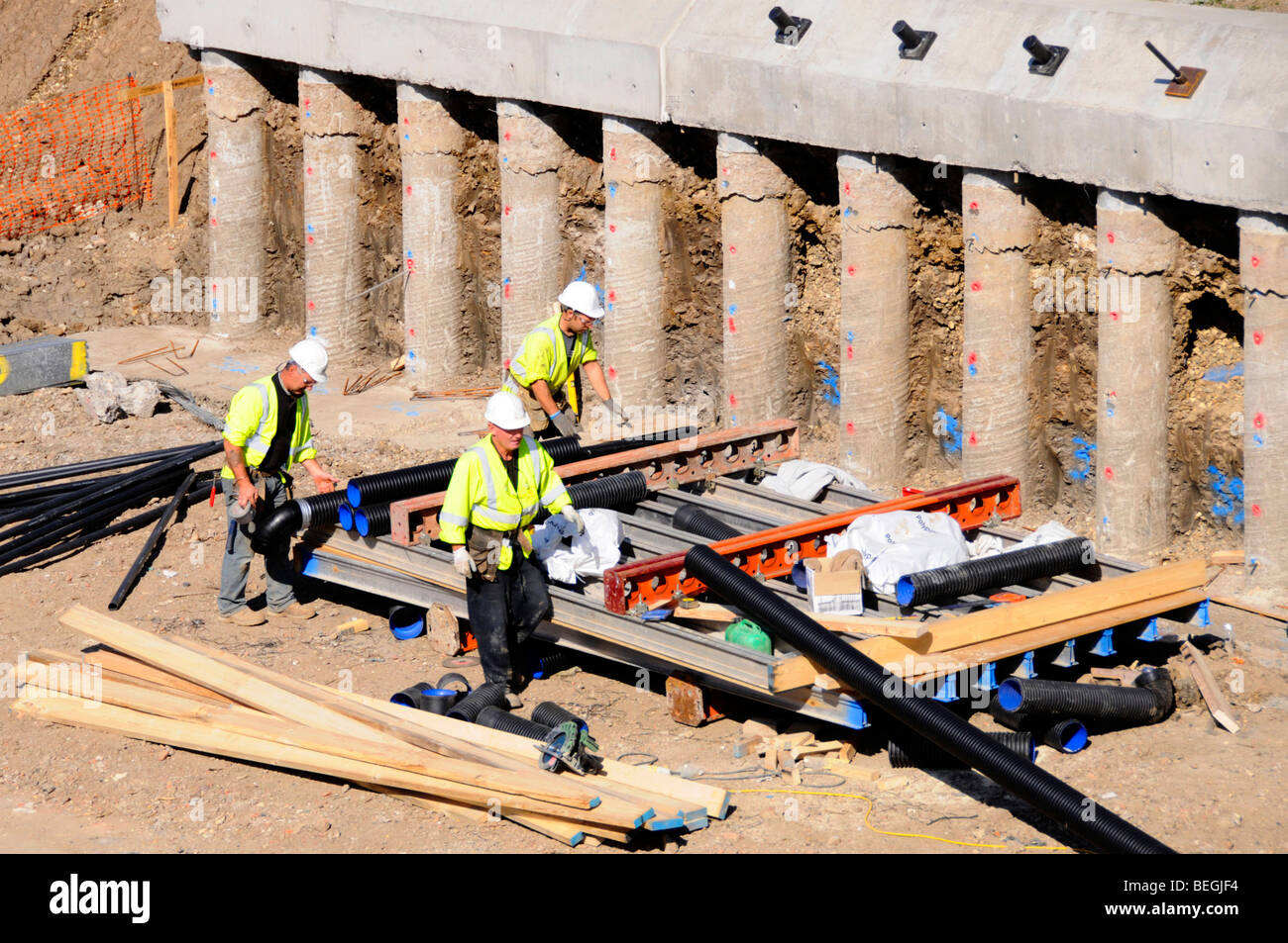Arbeiter Harthüte & Jacken mit hoher Sichtbarkeit ausgesetzt Betonpfähle & Pfahlkappe auf einem Teil einer Stützmauer Struktur für eine Autobahnbrücke England Großbritannien Stockfoto