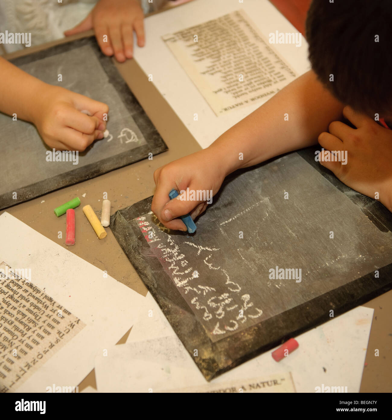 Kinder in einer Grundschulklasse schreiben mit Kreide auf alten altmodischen Schiefer Tabletten während der entscheidenden Phase zwei Geschichtsstunde Wales UK Stockfoto