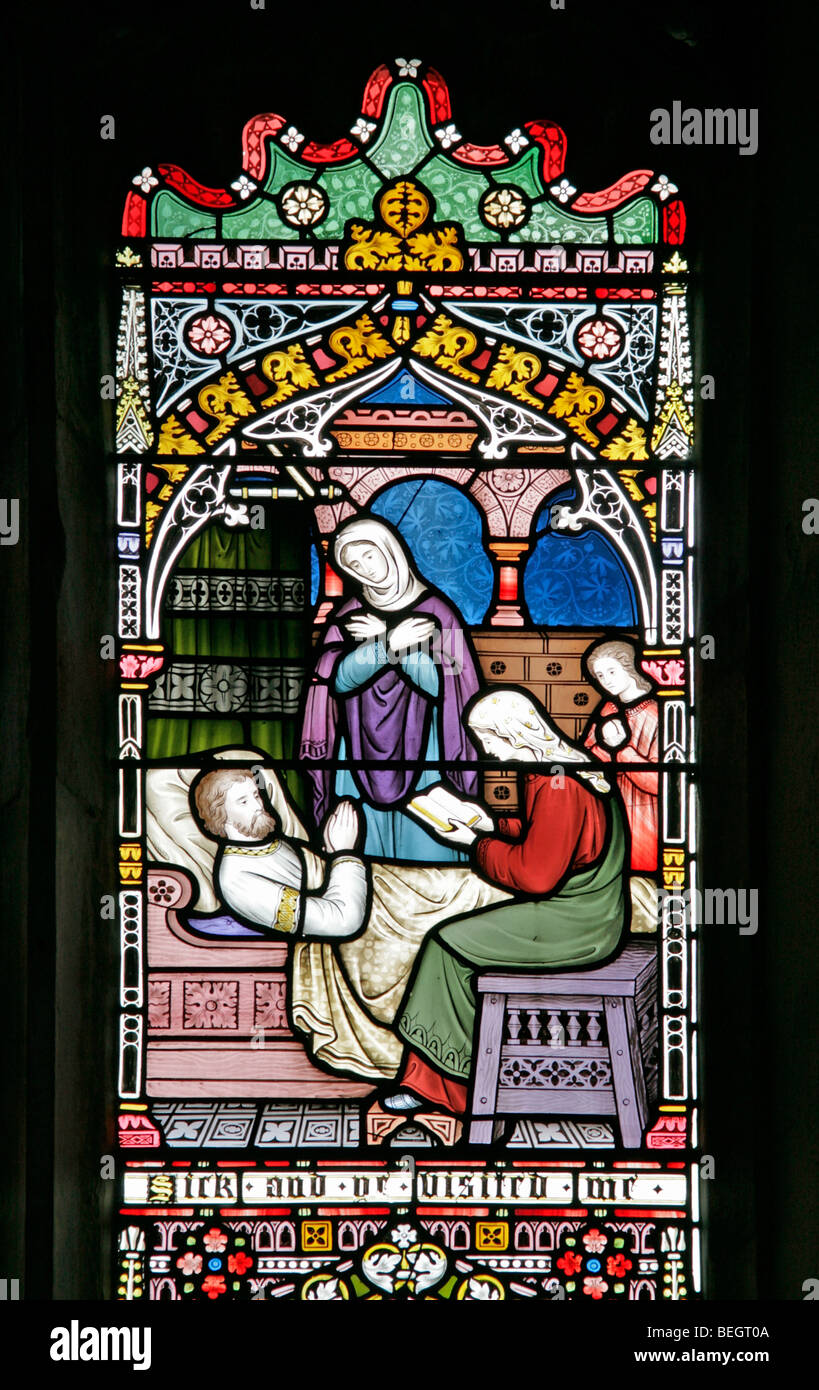 Ein Glasfenster von Frederick Preedy, das einen korporalen Akt der Barmherzigkeit (Besuch der Kranken), die Kirche der heiligen Jungfrau Maria, Gunthorpe, Norfolk, darstellt Stockfoto
