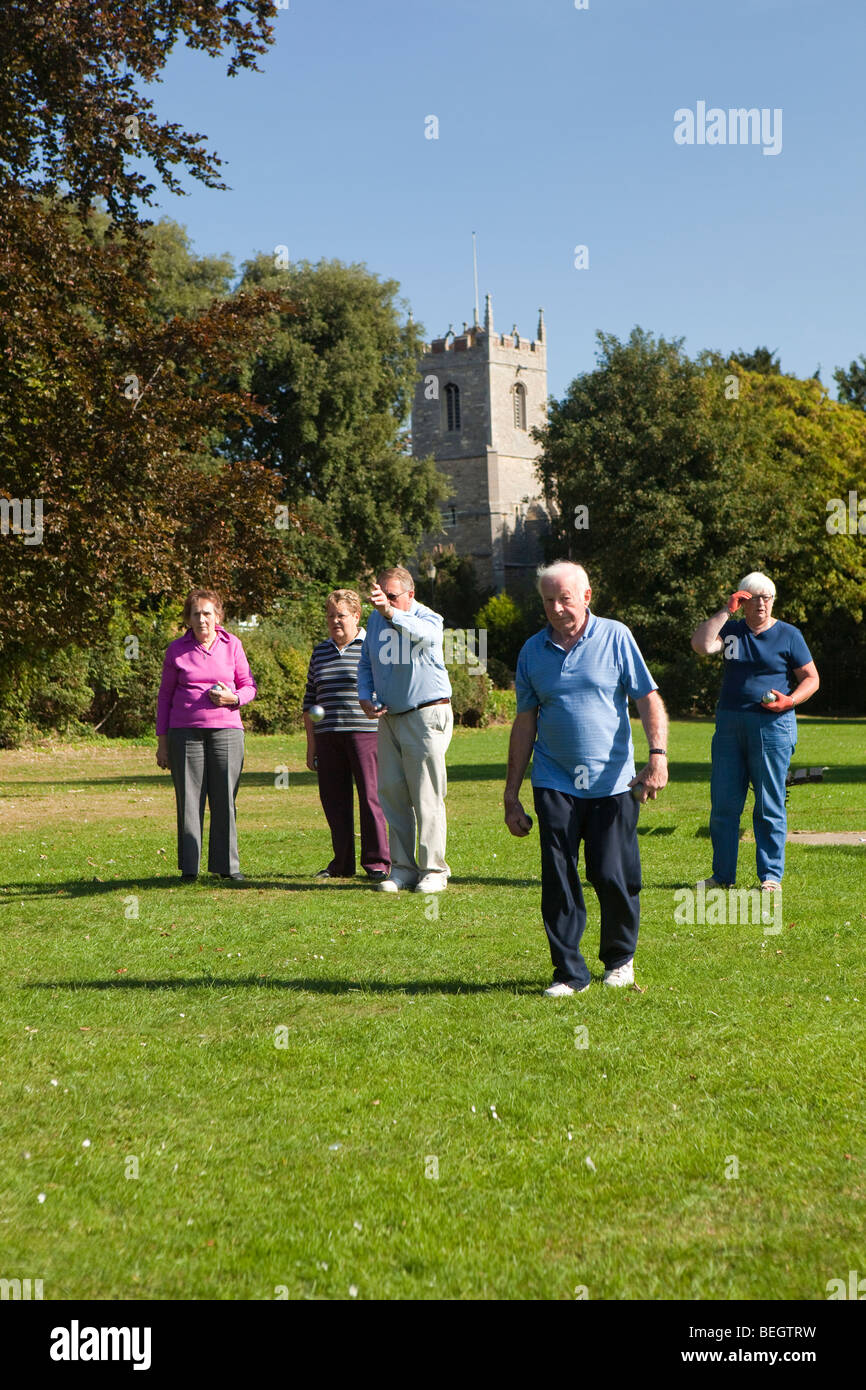 England, Cambridgeshire, Huntingdon, Hartford, Rentner spielen Boule am Flussufer grün unter Kirchturm Stockfoto