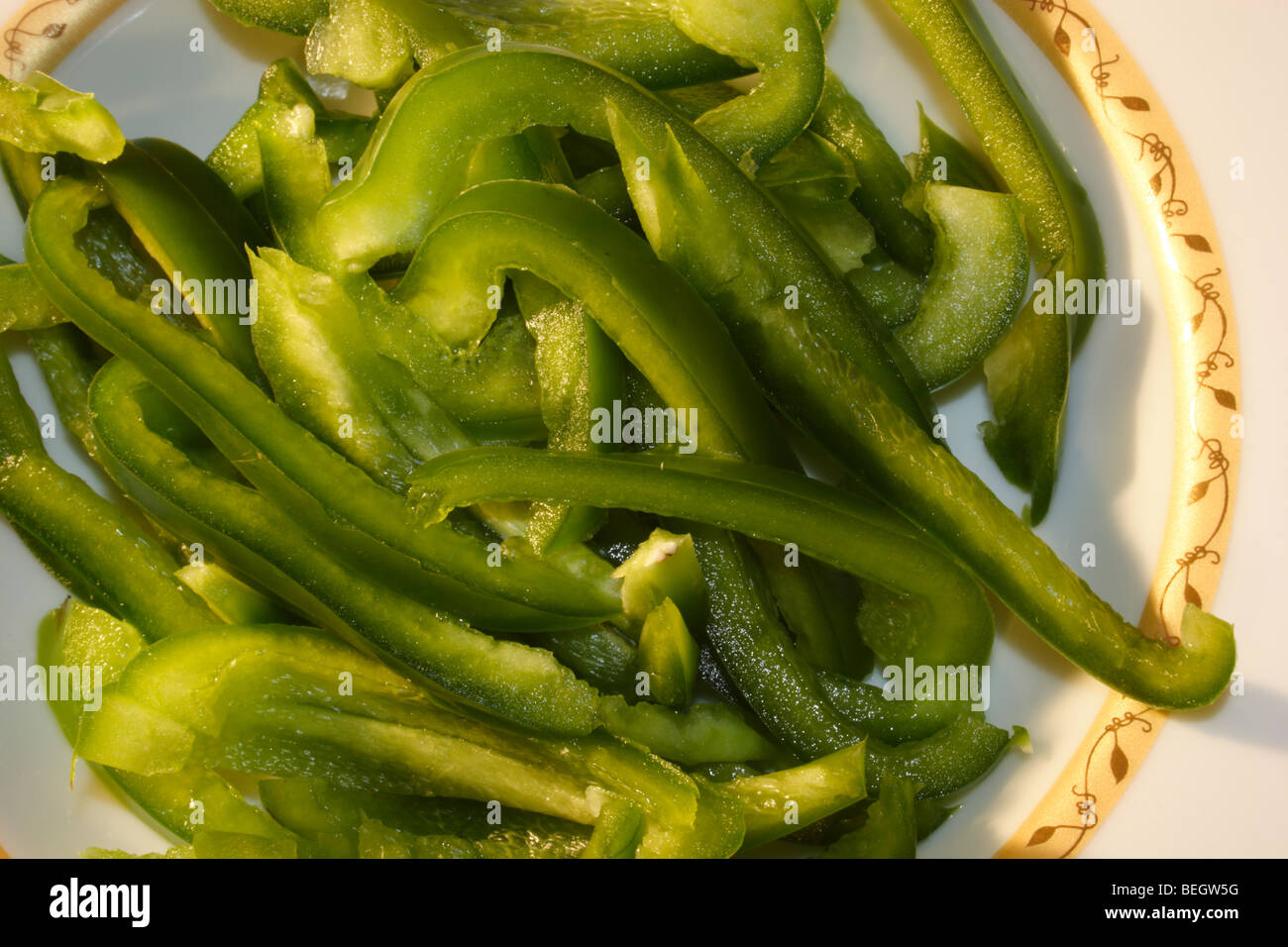 In Scheiben geschnittener grüner Paprika, der für Salat zubereitet wird Stockfoto