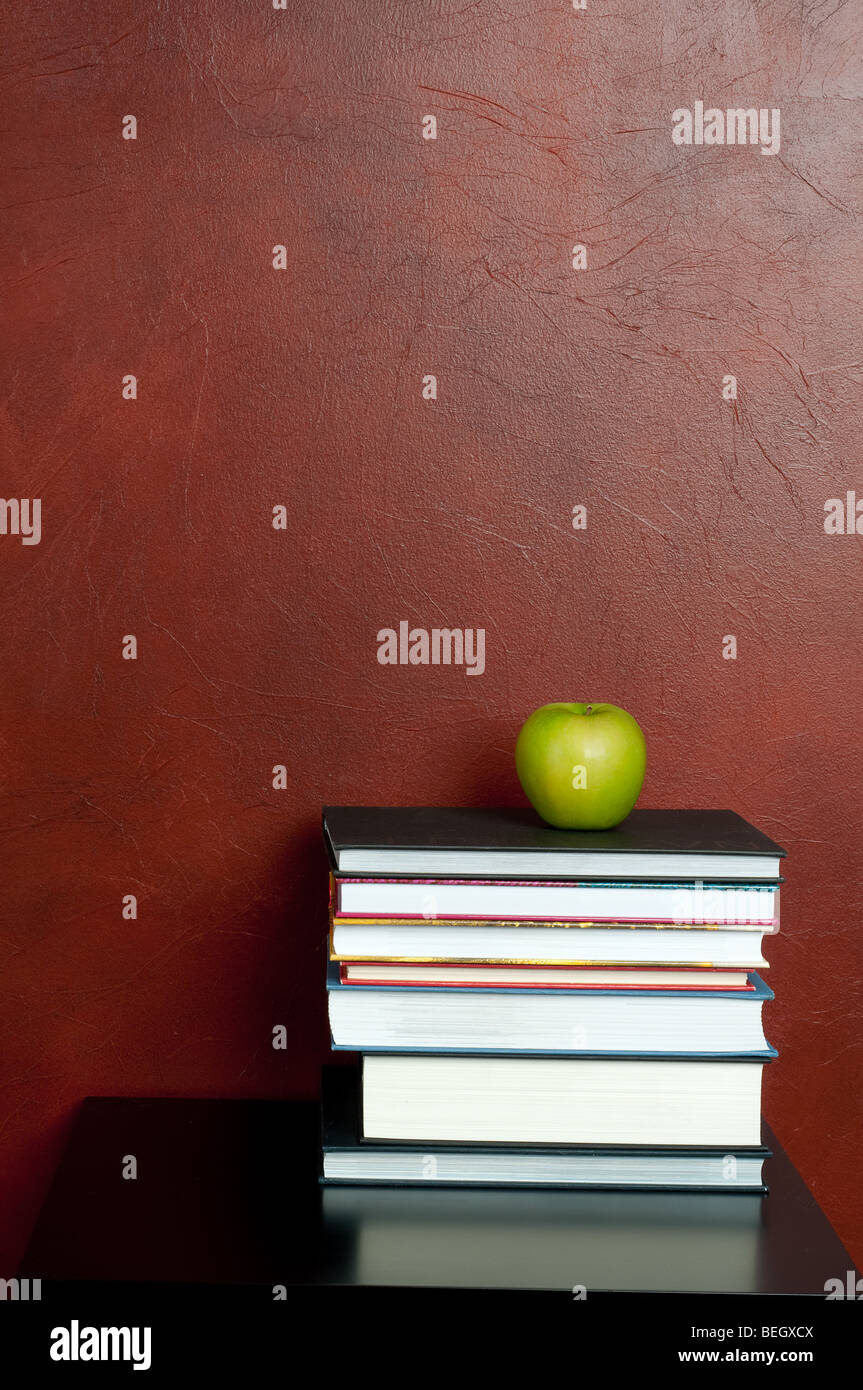 Vertikales Bild aus einem Stapel von Büchern mit grünem Apfel Stockfoto