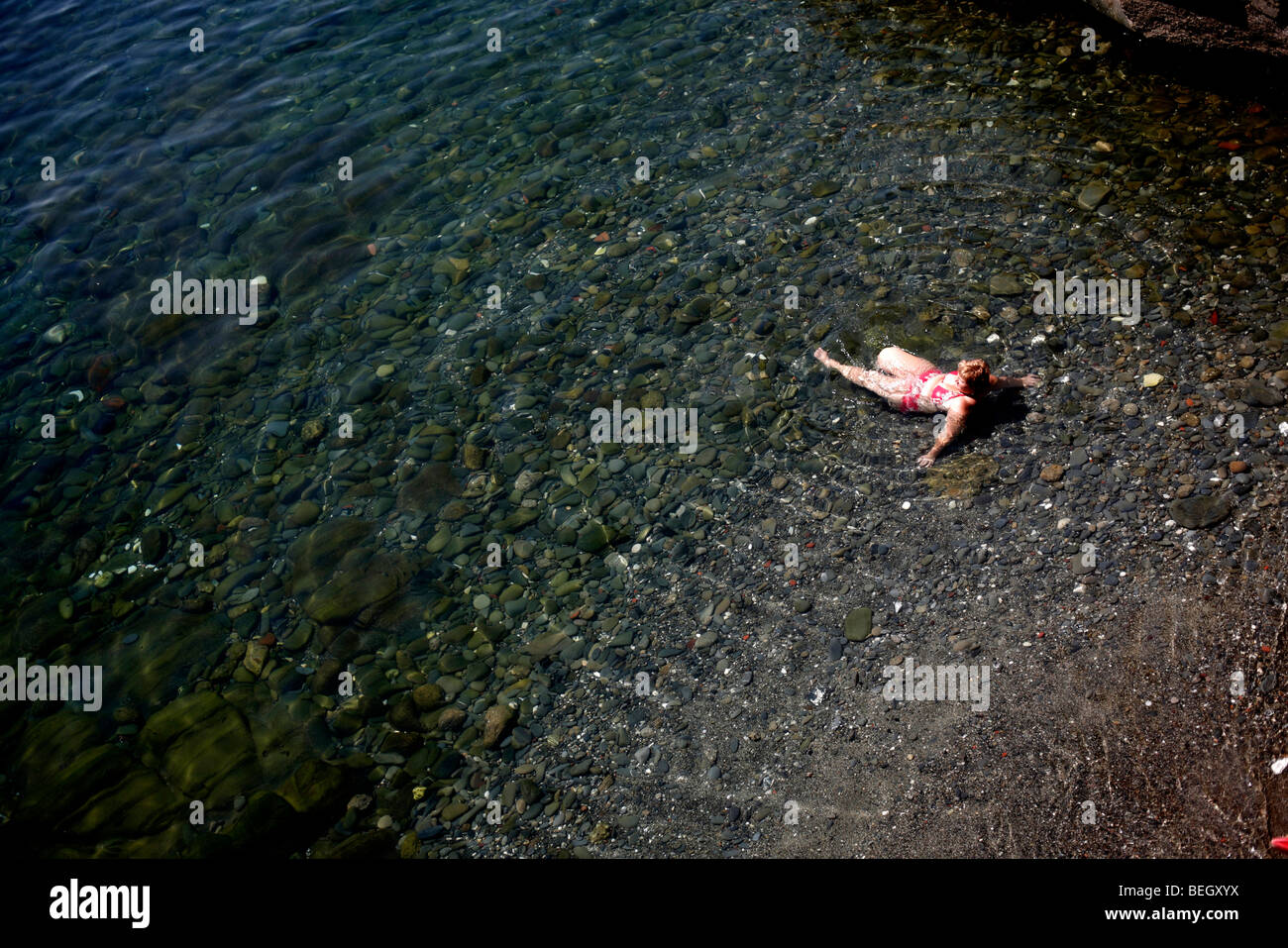Eine Frau liegt im Meer in Riomaggiore in der Region Cinque Terre an der italienischen Riviera oder Riviera di Levanto Stockfoto