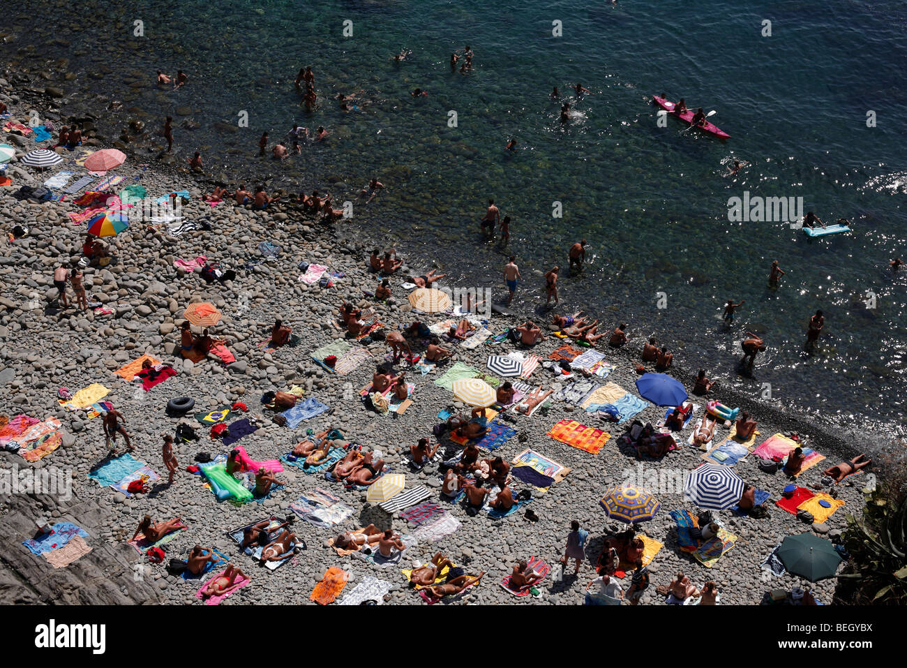 Sonnenanbeter am Strand von Riomaggiore in der Region Cinque Terre an der italienischen Riviera oder Riviera di Levanto Stockfoto