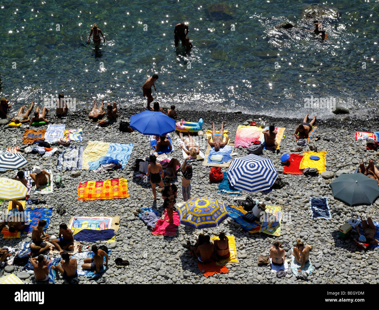 Sonnenanbeter am Strand von Riomaggiore in der Region Cinque Terre an der italienischen Riviera oder Riviera di Levanto Stockfoto