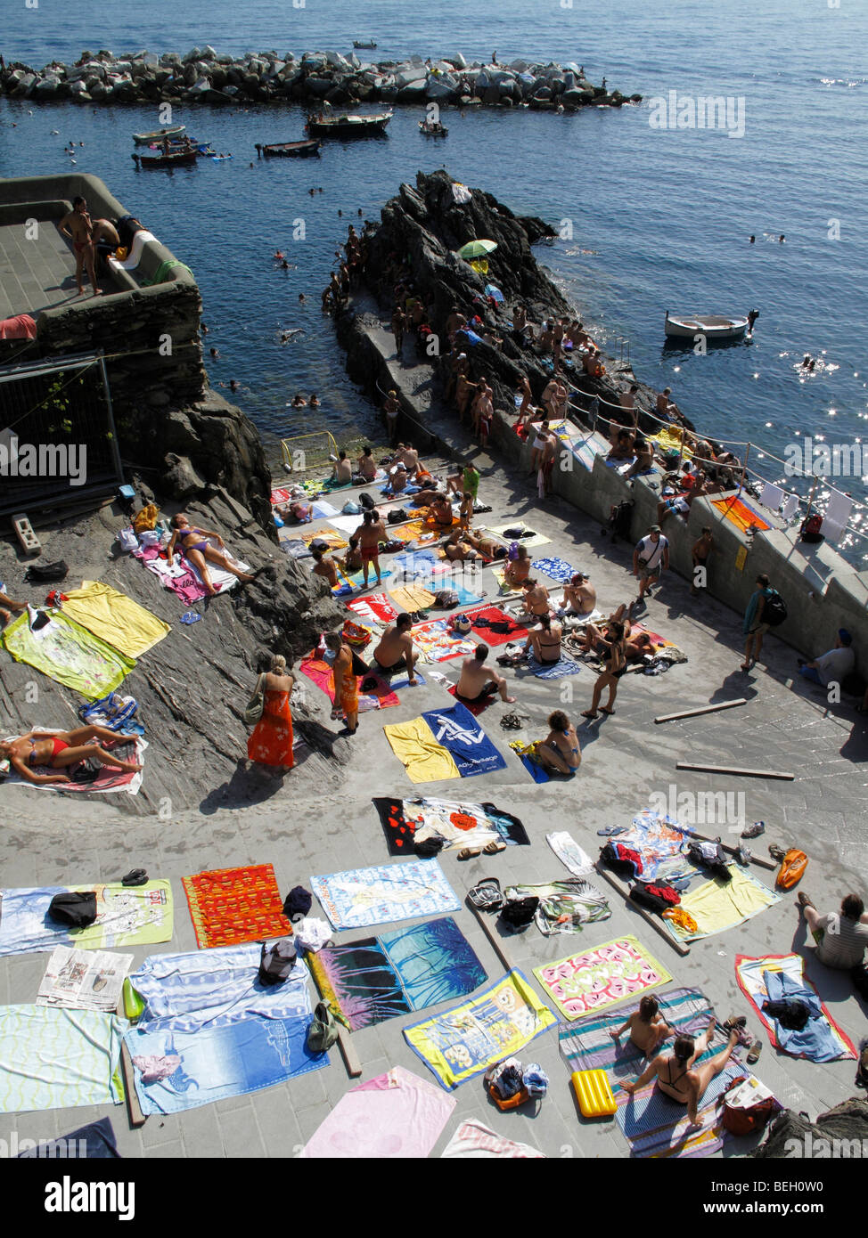 Handtücher von Sonnenanbeter auf dem Slipway am Manarola in der Region Cinque Terre an der italienischen Riviera oder Riviera di Levanto angelegt Stockfoto