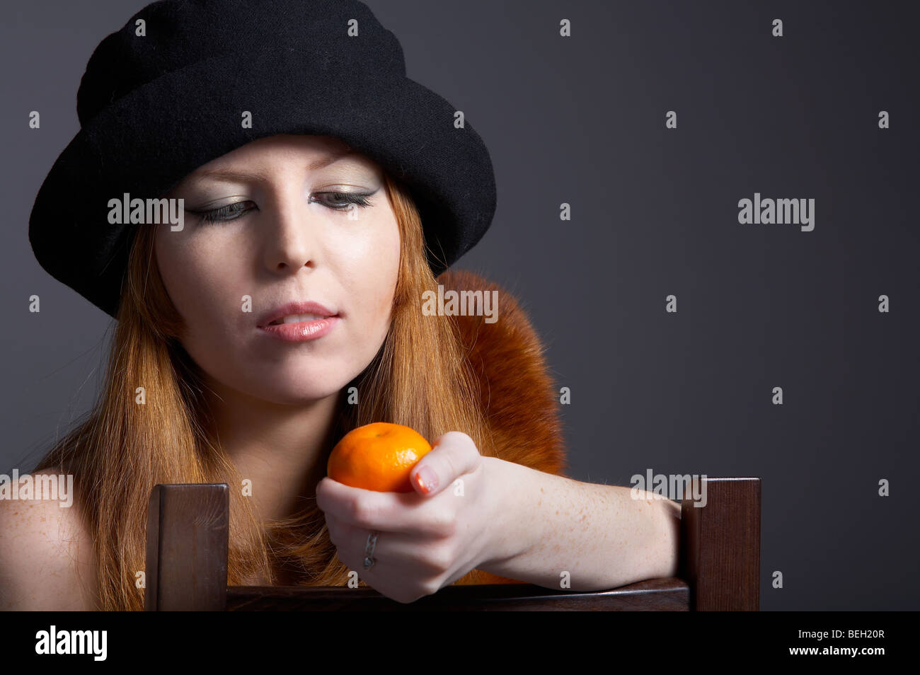 Portrait von schöne rothaarige blasse Haut Model in Pelz Fuchs Schal und schwarzen Hut mit mandarine Stockfoto
