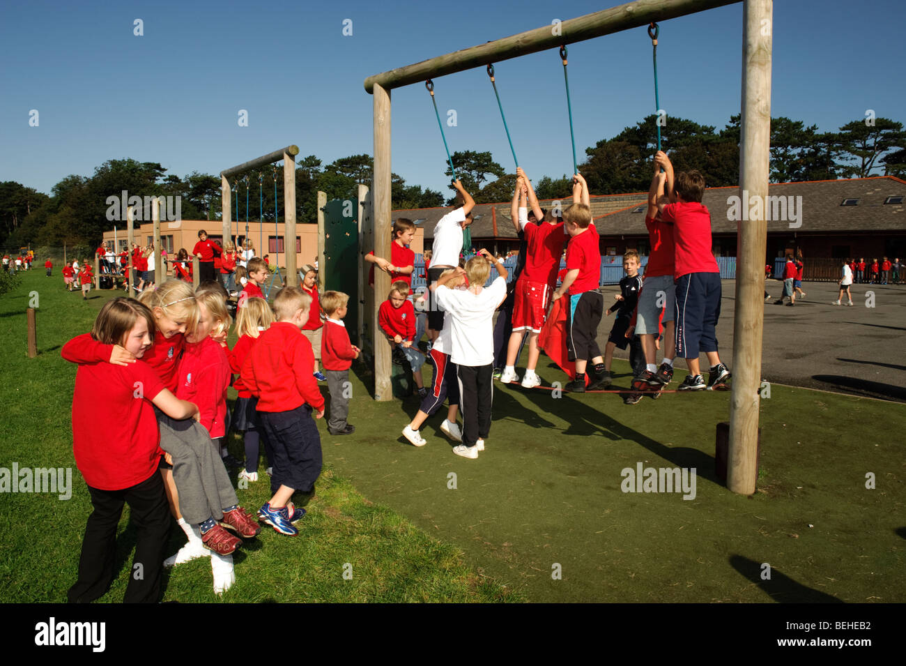 Junge Kinder in den Pausen spielen auf Kletterseile auf Spielplatz an einem sonnigen Tag in einer walisischen Sprache mittlere Grundschule Stockfoto