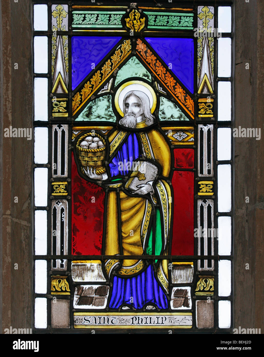 Ein Buntglasfenster von Joseph Grant von Costessey, das Philipp den Apostel darstellt, der einen Korb mit Broten hält, die Allerheiligenkirche, Wighton, Norfolk Stockfoto