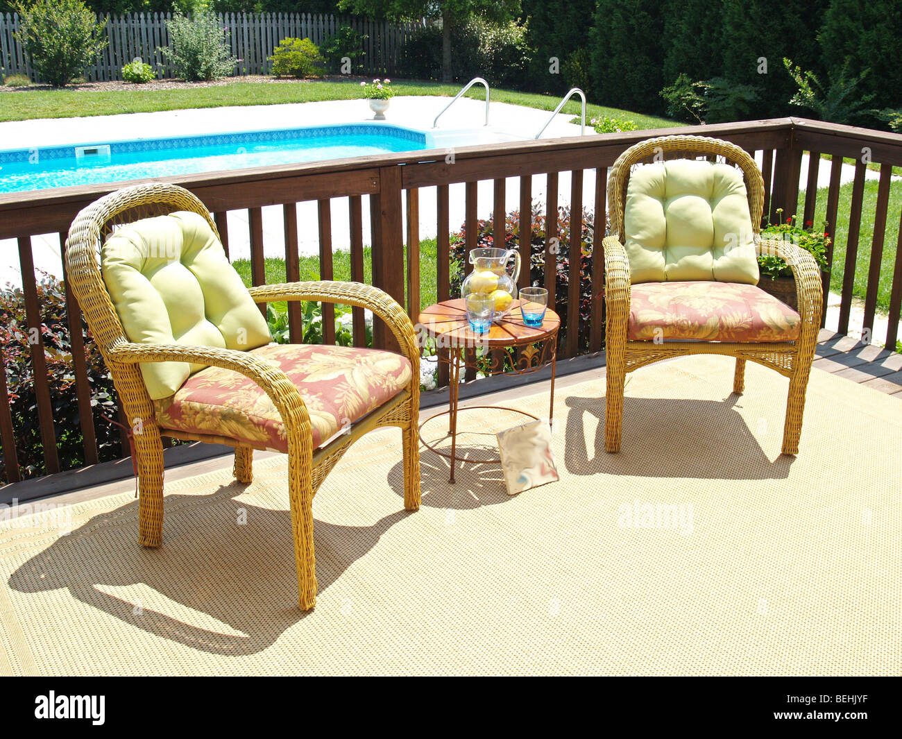 Zwei bequeme Stühle auf der Terrasse mit Blick auf einen Pool im Garten Stockfoto