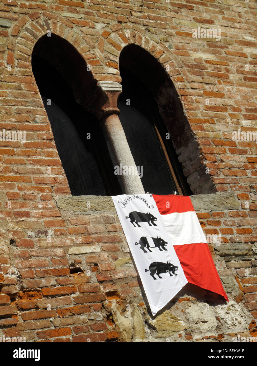 Gewölbtes Fenster mit einer lokalen Contrade Fahne hing unter in Cividale del Fruili in Norditalien Stockfoto