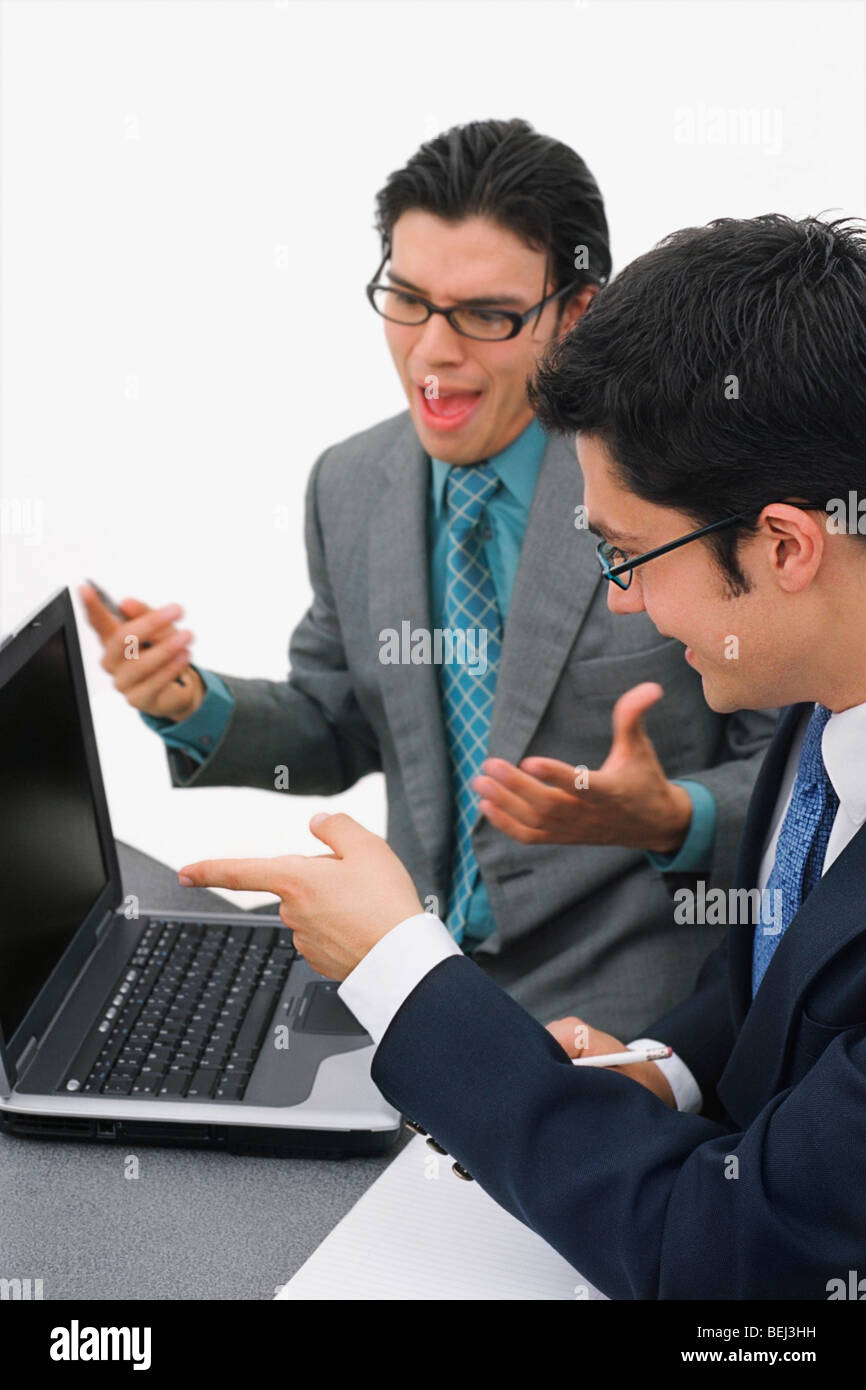 Zwei Geschäftsleute, die vor einem Laptop in einem Meeting sitzen Stockfoto