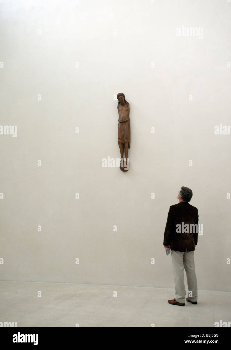 Man betrachtet man aus Holz geschnitzte Statue Christi in karge Innenraum des Kolumba Museum in Köln Stockfoto