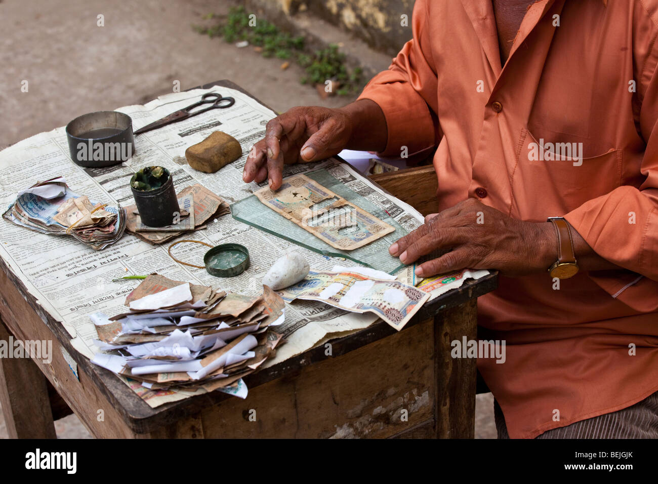 Mann, die Reparatur von alten und beschädigten Papiergeld in Khulna Bangladesch Stockfoto