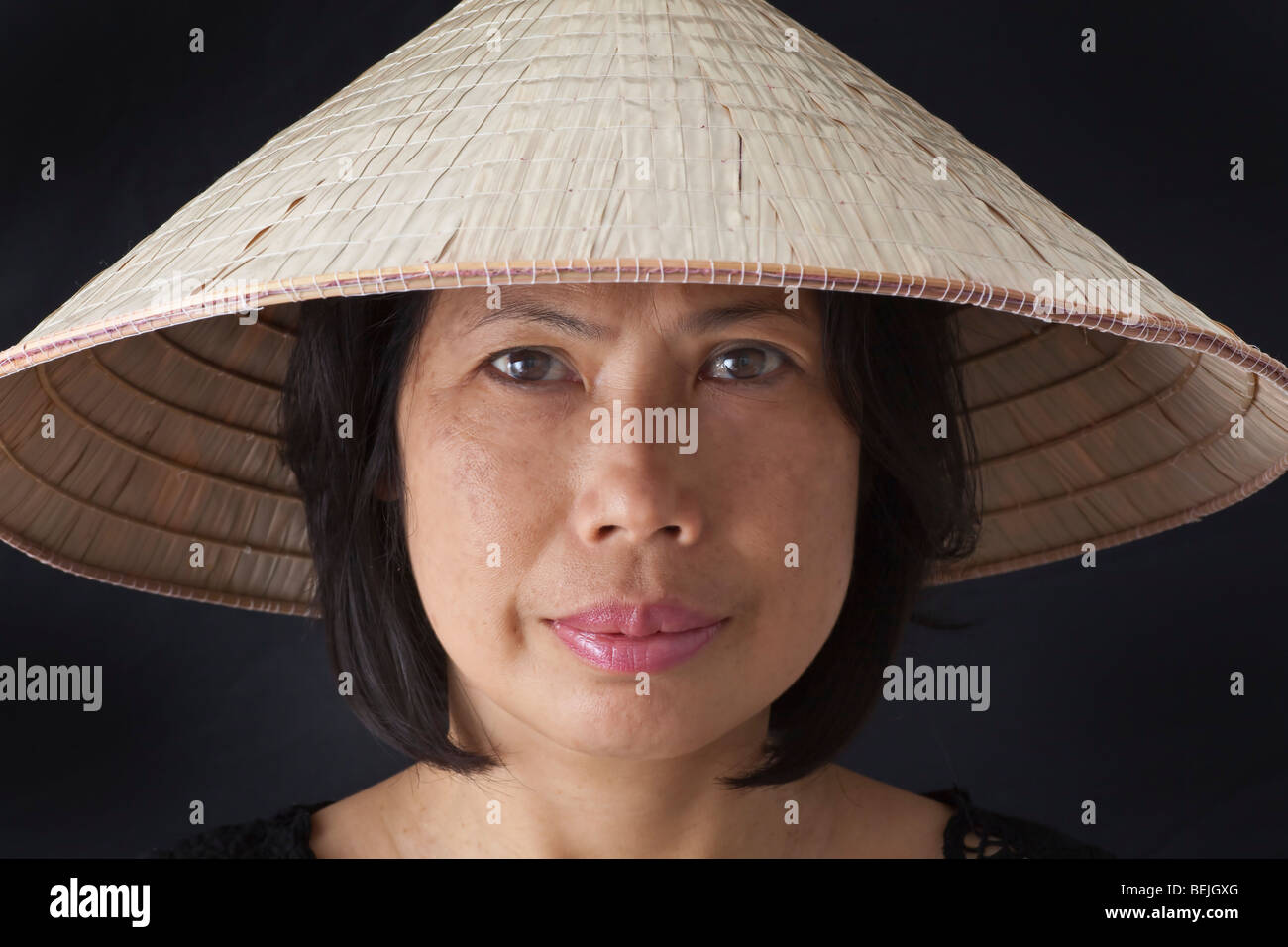 Eine orientalische Dame tragen des gemeinsamen konischen gewebten Hutes so weit verbreitet in Sout Ostasien vor allem Vietnam Stockfoto