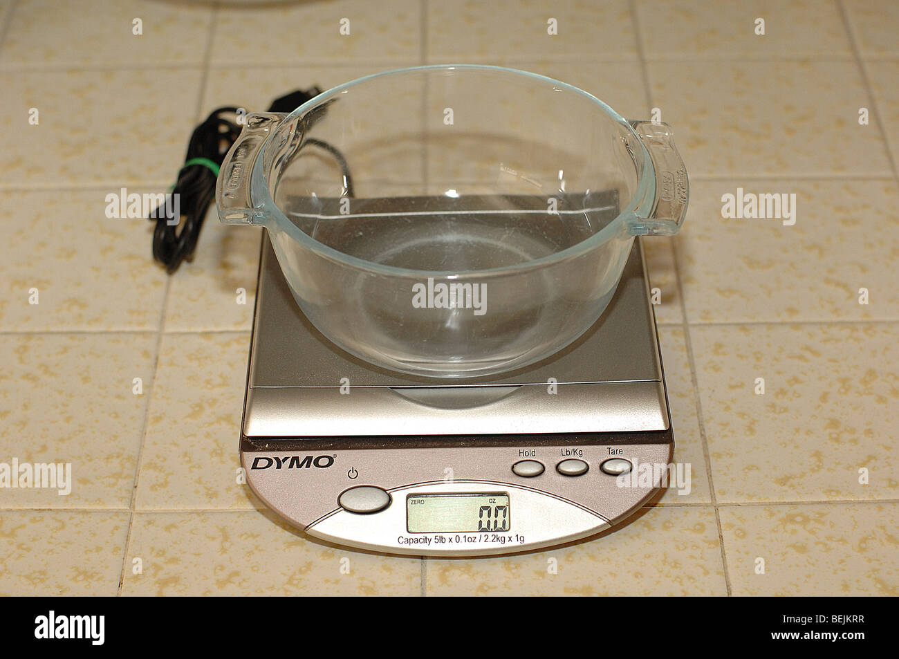 Eine Glasschüssel auf eine digitale Waage sitzen auf einer Fliese. Stockfoto