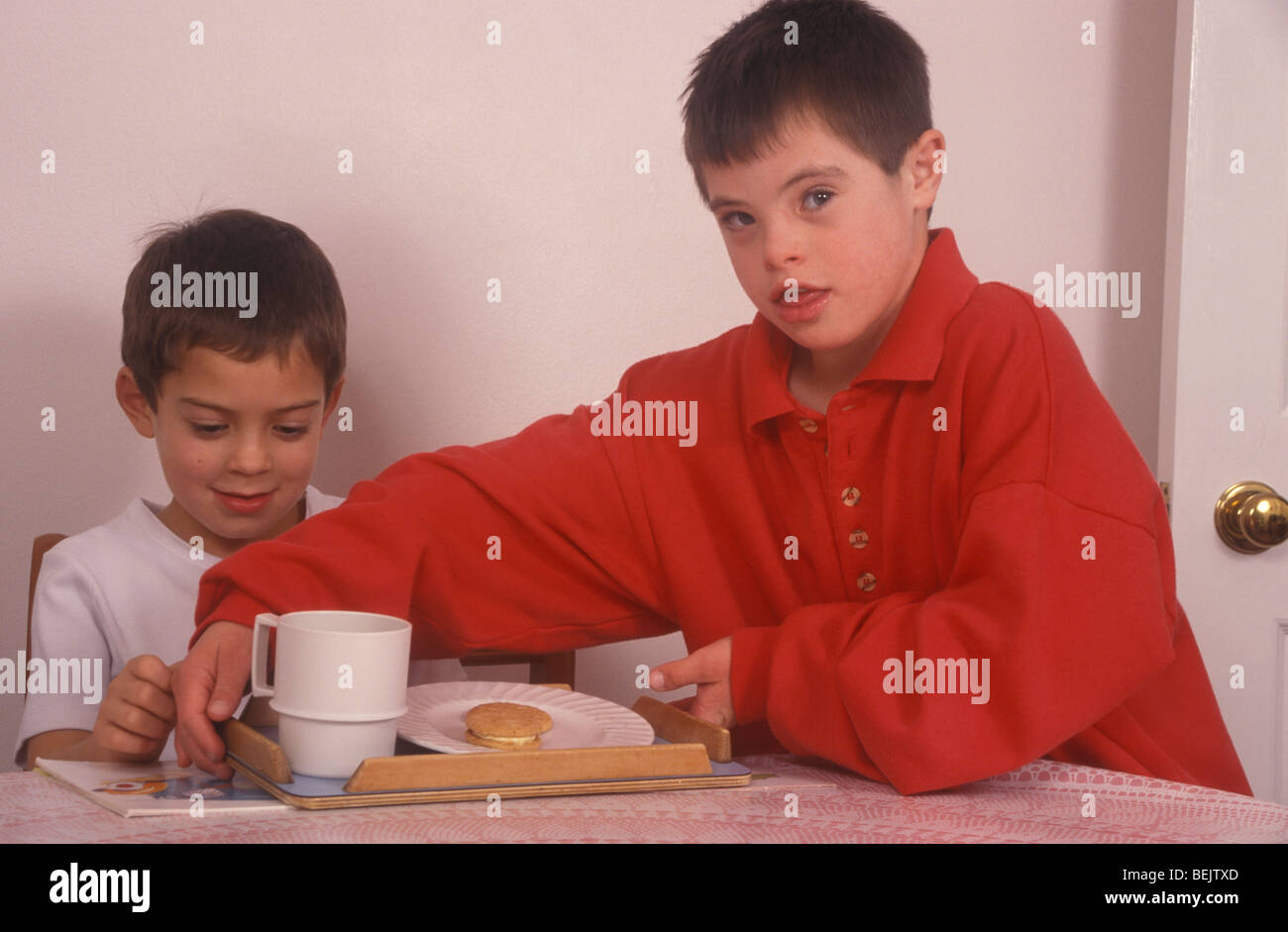 kleiner Junge mit Down-Syndrom geben Tee an einen Freund Stockfoto