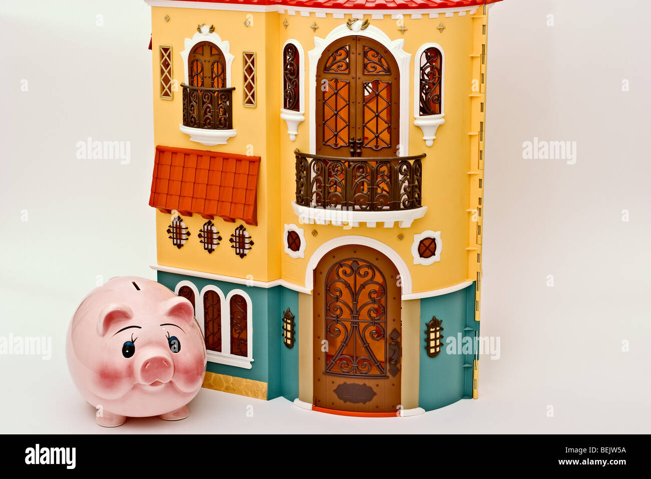 Kleine rosa Sparschwein neben einem aufwendigen europäischen Stil-Puppe-Haus Stockfoto