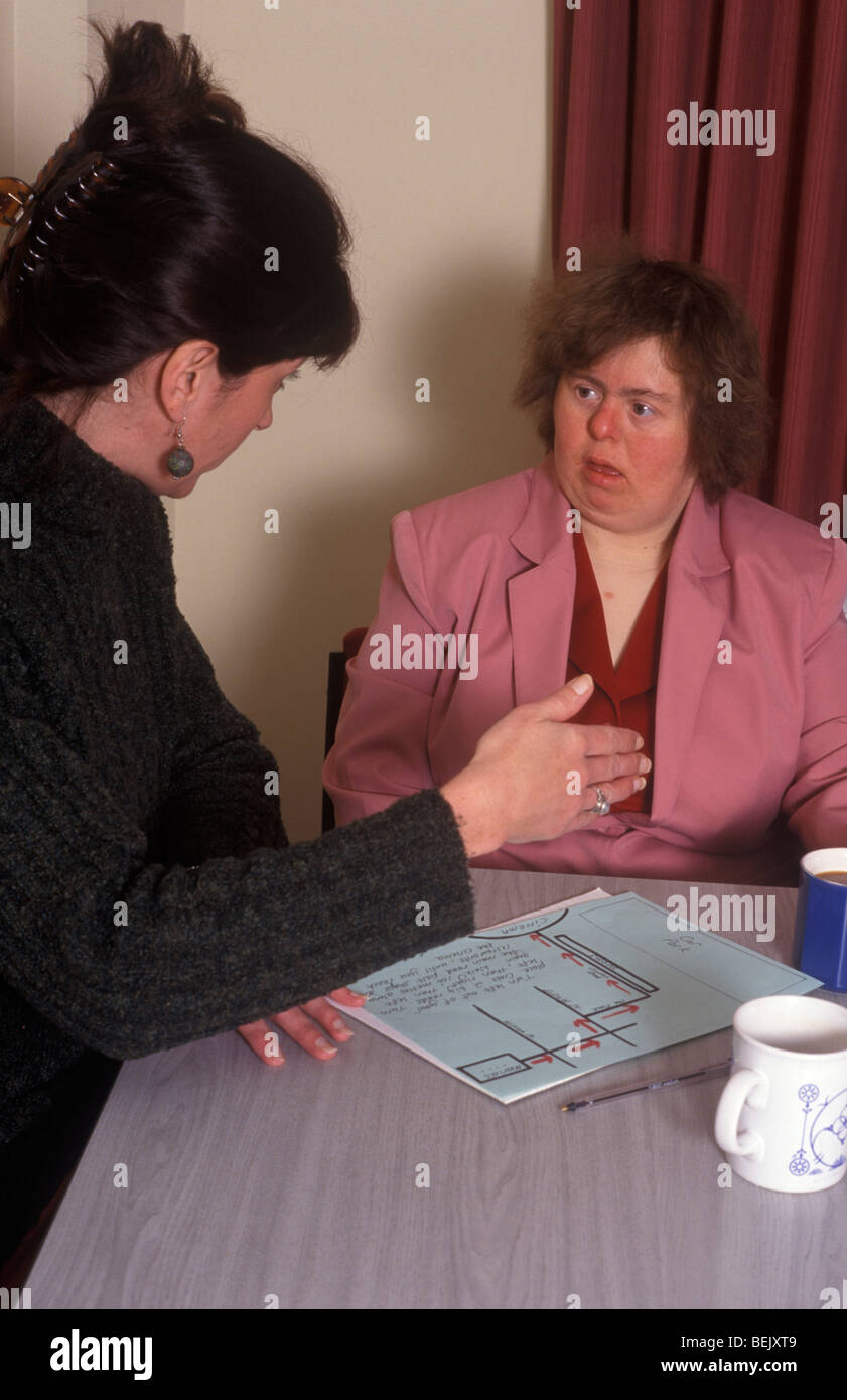Frau mit Down-Syndrom im Gespräch mit einer Sozialarbeiterin oder Helfer Stockfoto