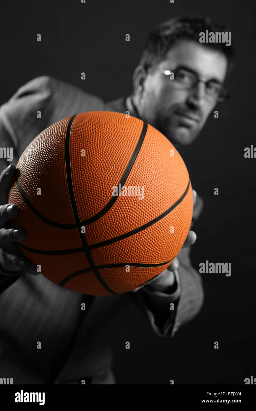 Geschäftsmann mit Basketball Ball, Teamarbeit, Führung Metapher Stockfoto