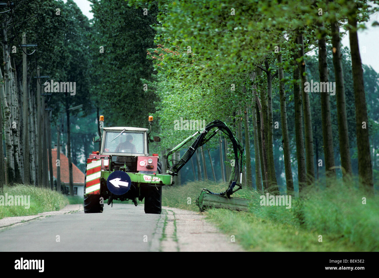 Traktor mäht am Straßenrand Schulter, Belgien Stockfoto