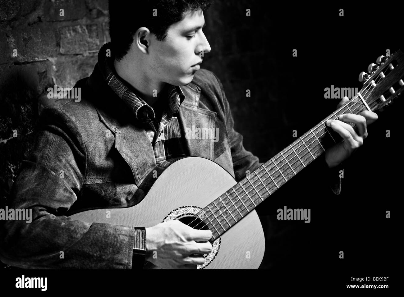 Junger Mann an der Gitarre zu spielen. Dunkle Farben schwarz und weiß. Stockfoto