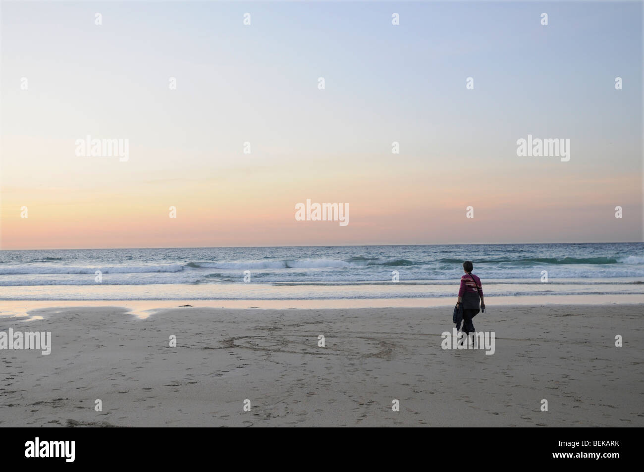 Eine 40 Jahre alte Frau geht am Cornish Strand bei Sonnenuntergang Stockfoto