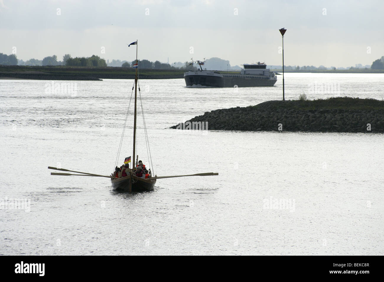 Antike & Modern - kleine Viking Longboat an der Fluss-Wand am Reenactment in Tiel in den Niederlanden - barge im Hintergrund Stockfoto