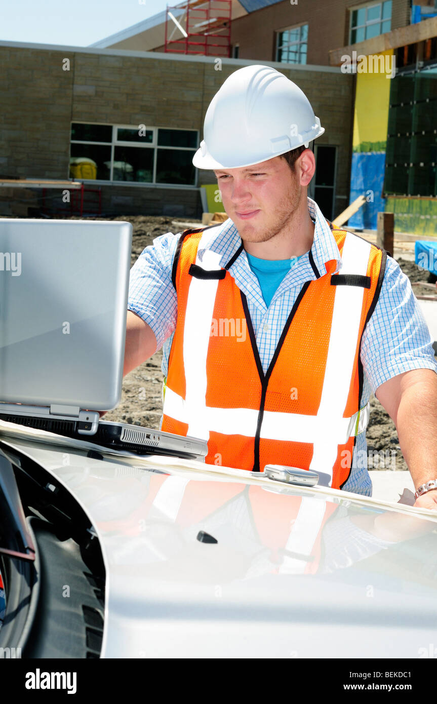 Männliche Bauingenieur Sachverständiger Architekt mit einem Laptop auf einer Baustelle tragen Sicherheit Hi Vis Weste und Helm Stockfoto