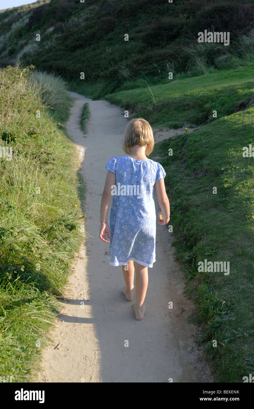 Ein sechs Jahres altes Mädchen Spaziergänge auf einen Sandweg in der Landschaft Stockfoto