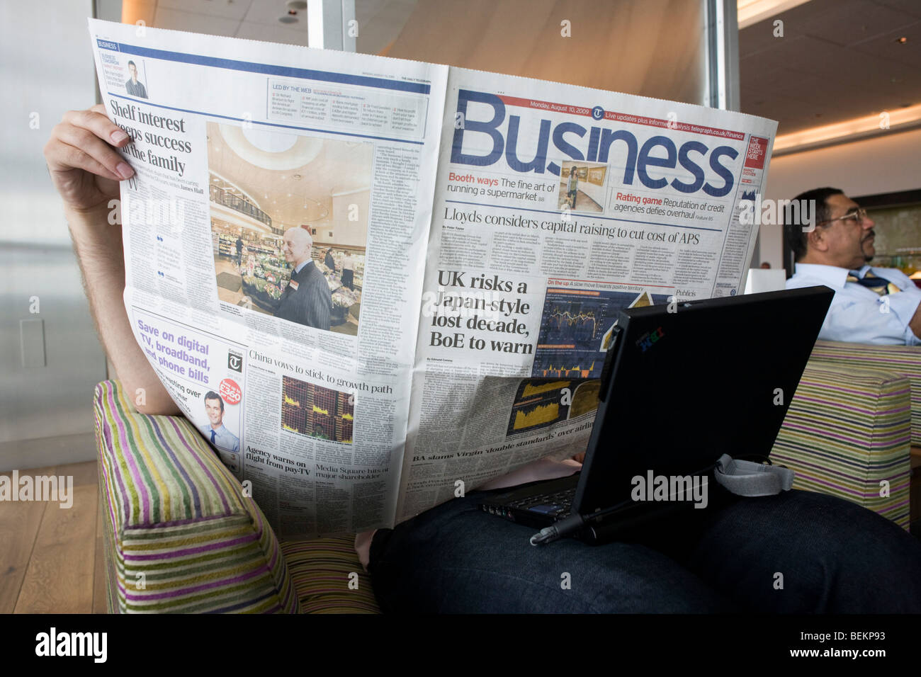 Ein Business-Class-Passagier versteckt sein Gesicht beim Lesen des Wirtschaftsteil des Daily Telegraph in BA Terminal 5 Lounge. Stockfoto